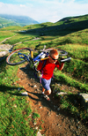 Chamonix, Haute-Savoi, Rhne-Alpes, France: green slopes and mountainbiker carrying his bike on the trail of Tour du Mont Blanc - photo by S.Egeberg